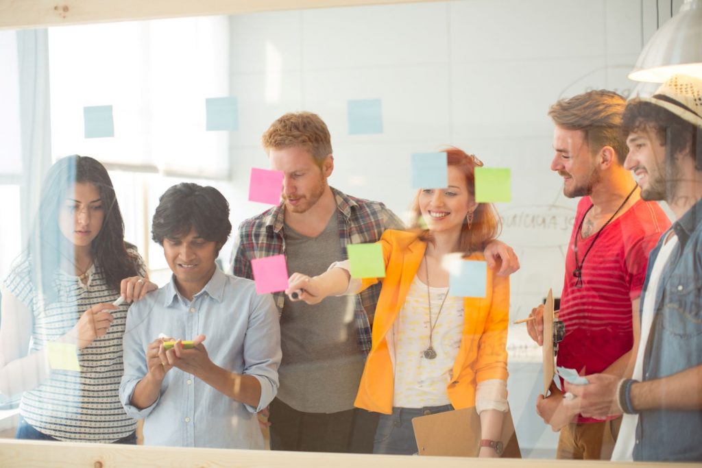 group working on a glass sticky notes board