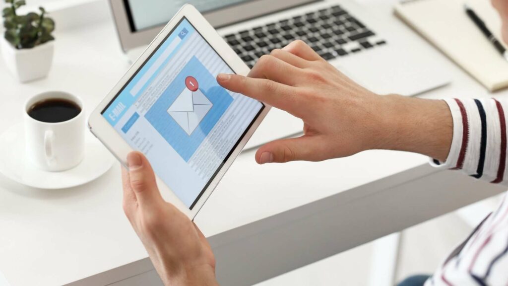 Image of a person clicking on an email on a tablet while at the desk.